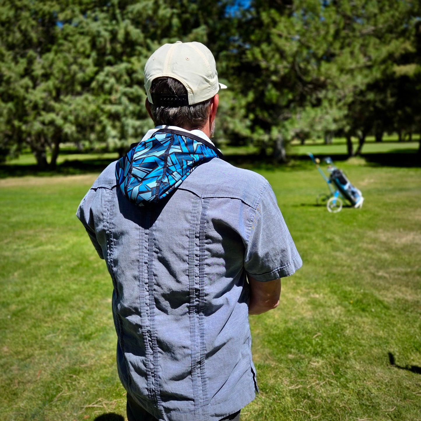 Man with Black and Blue hood on golf course.