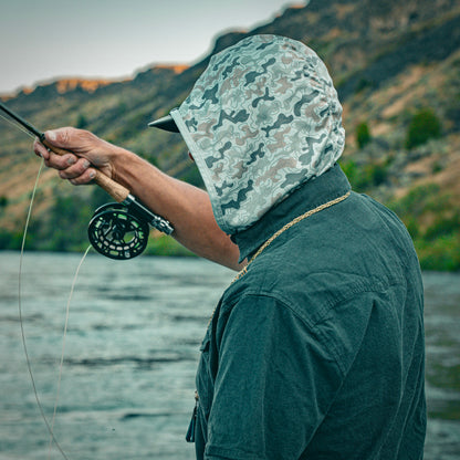 Person fly fishing with a camo hood in a natural setting