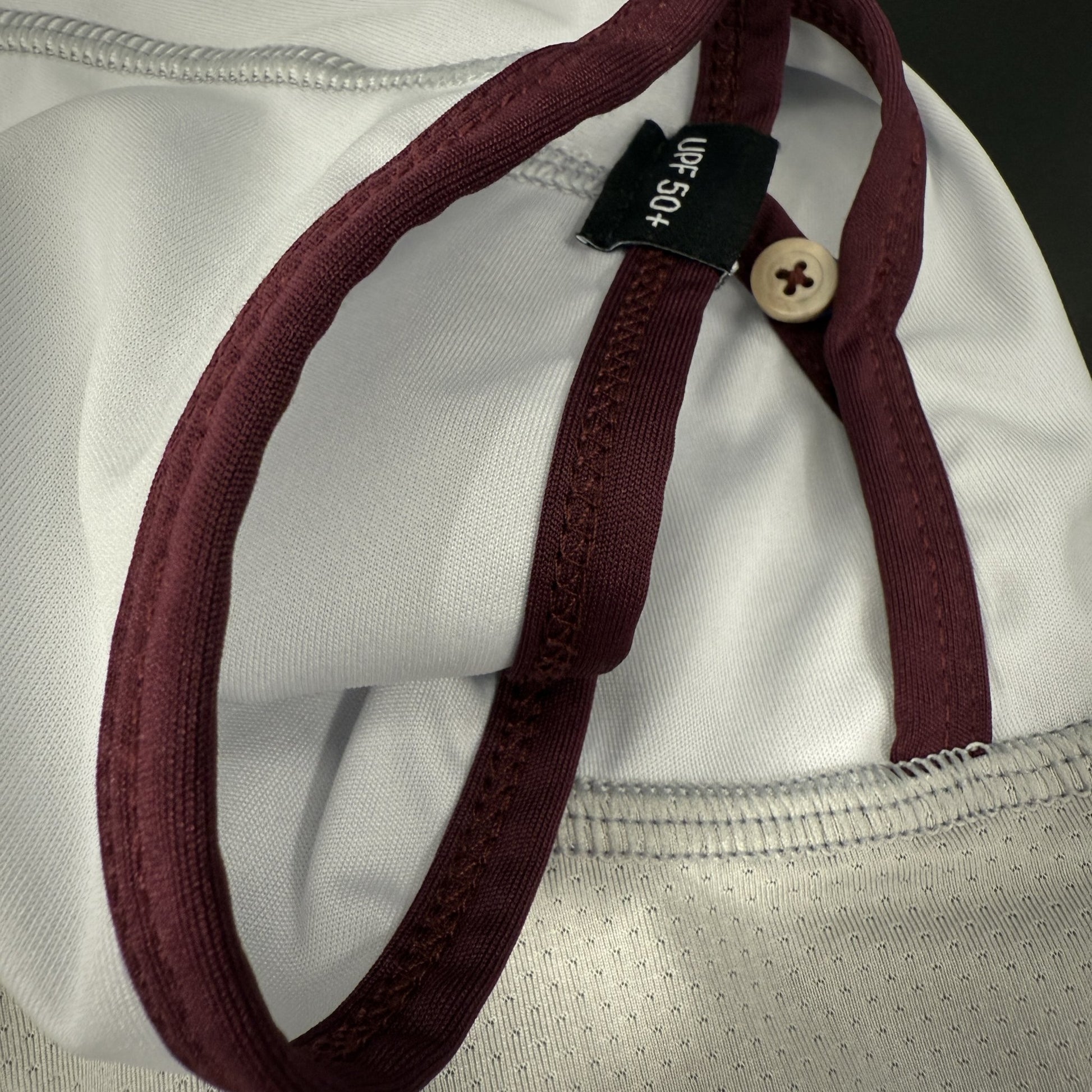 Close up of light grey and wine button closure.